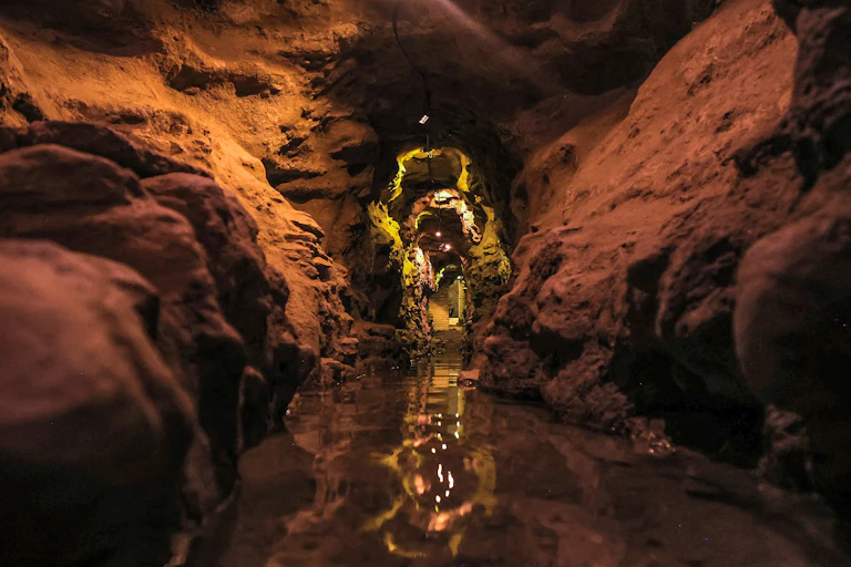 A tunnel with water inside it and lights at the end