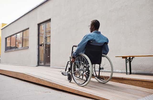 man in wheelchair going up ramp to doorway