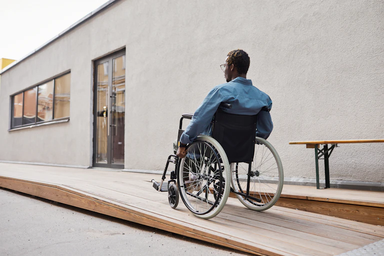 man in wheelchair going up ramp to doorway