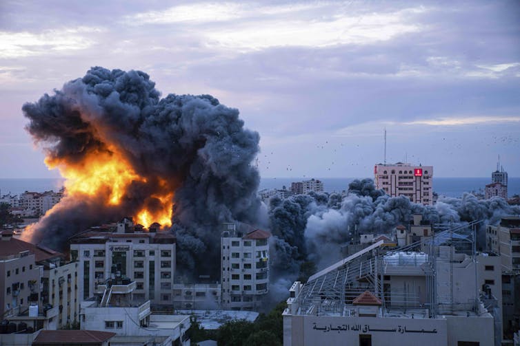 Fumaça e chamas subindo de um prédio em uma cidade.