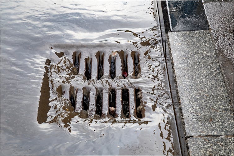 Rain water flows down a street drain