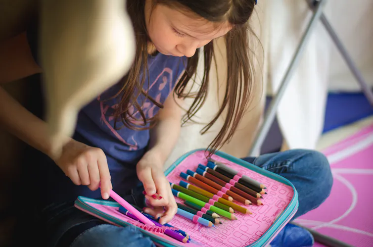 Une fille regarde un jeu de crayons de couleur