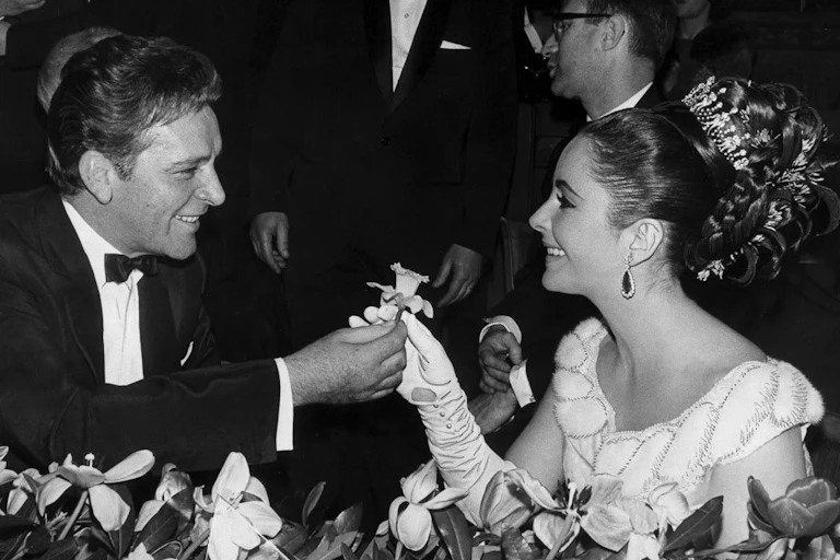 A man in black tie and a glamorous woman in diamonds in a restaurant.