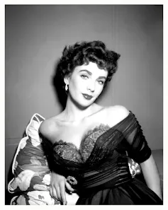 A very glamorous dark-haired young woman in a revealing dress and come hither expression.