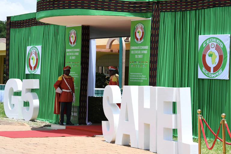 Men in ceremonial military dress stand guard at an entrance
