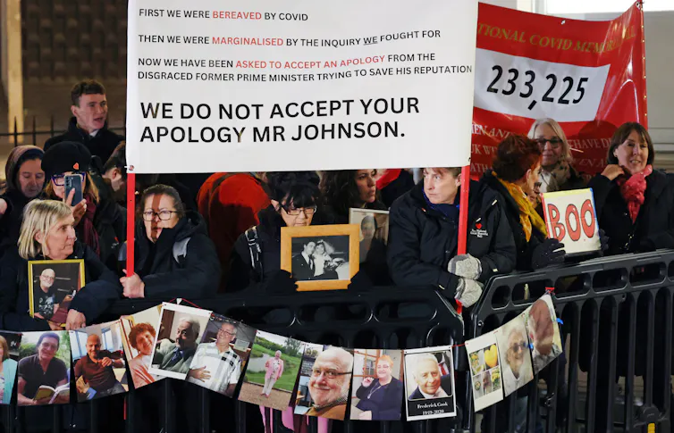 Protestors hold up photos of family members who died from COVID and hold up a banner reading 'we do not accept your apology Mr Johnson'.