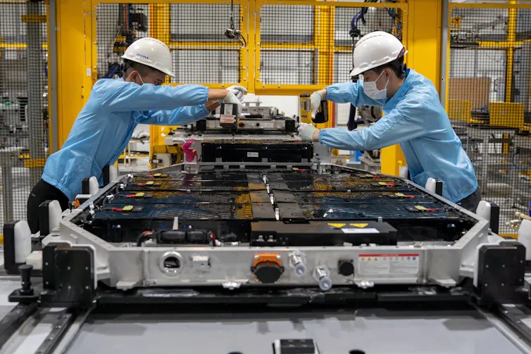Two workers in an electric car battery factory