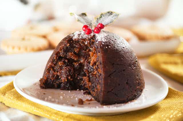 A Christmas pudding, from which a slice has been cut, revealing its raisin-filled rich interior.