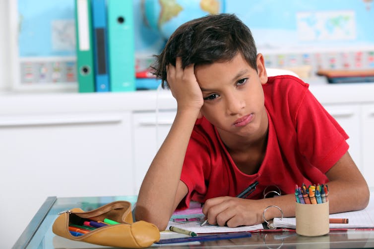 A child looks bored at his desk.