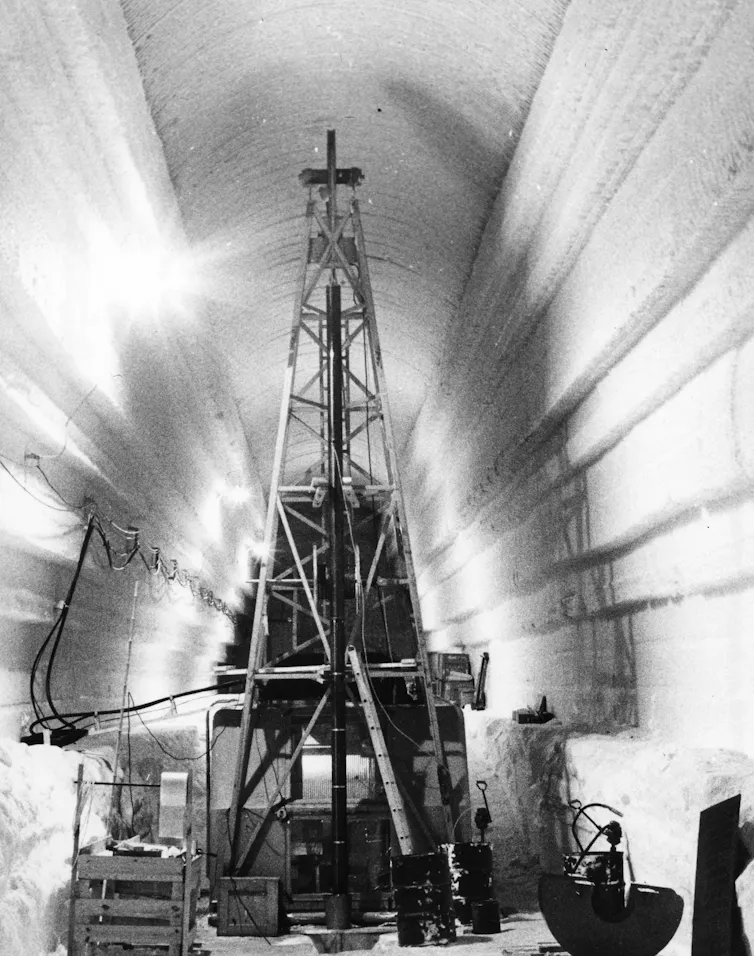 A drilling rig in a trench dug deep into the ice .