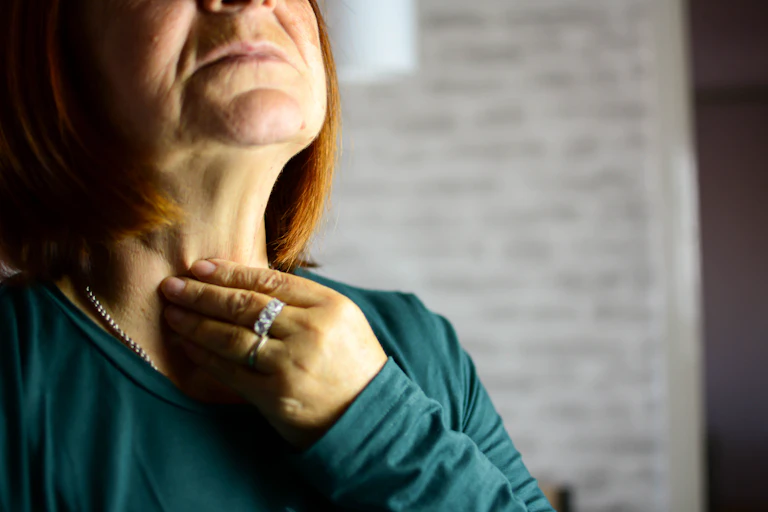 woman puts hand up to her throat