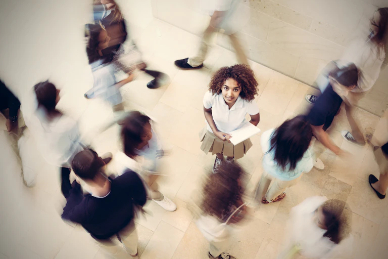 Nervous student standing still in busy private school hallway