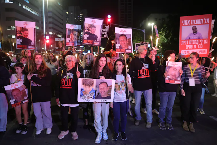 Israeli people demonstrate holding up pictures of hostages and demanding the government secure their release.