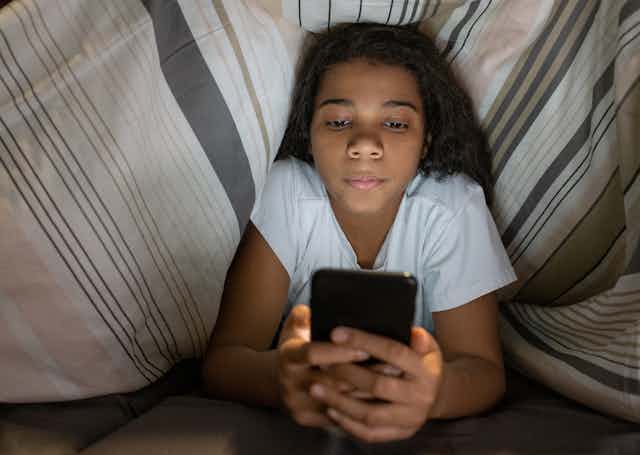 Girl in bed looking at mobile phone
