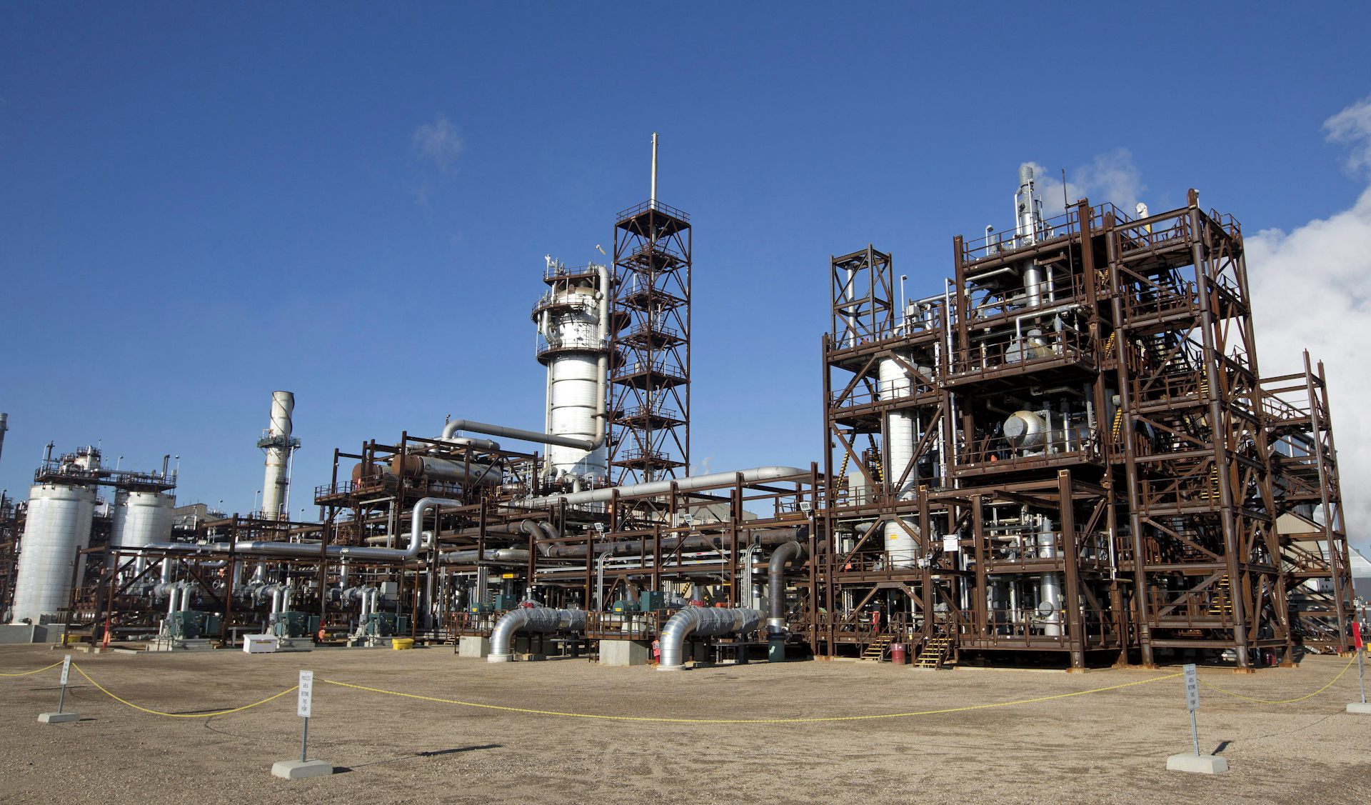 A large industrial plant is seen against a blue sky.