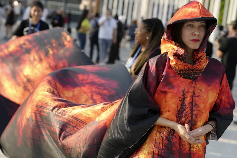 A woman seen in a billowing dress with a long train printed with wildfire.