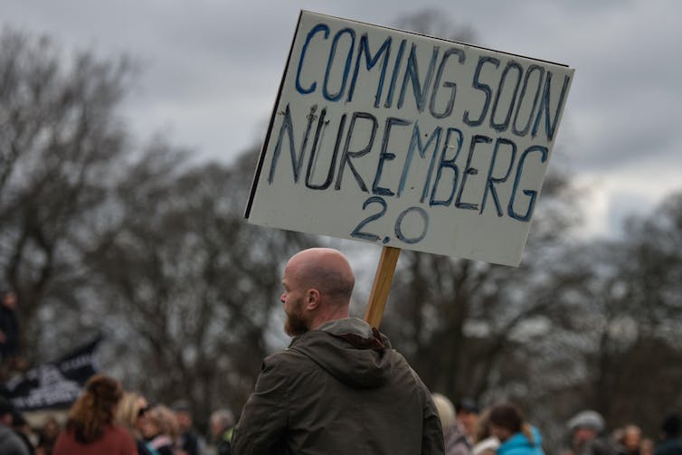 A protestor holding a sign that reads 'coming soon Nuremberg 2.0'.