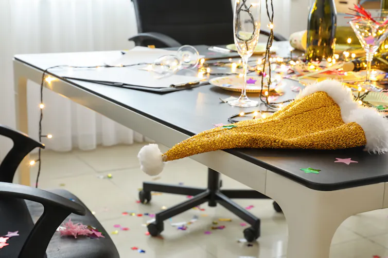 Messy table with empty bottles and glasses, santa hat, string of lights.