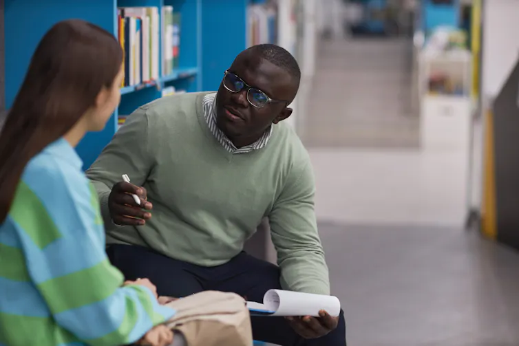 A man gives advice to a woman in a library.
