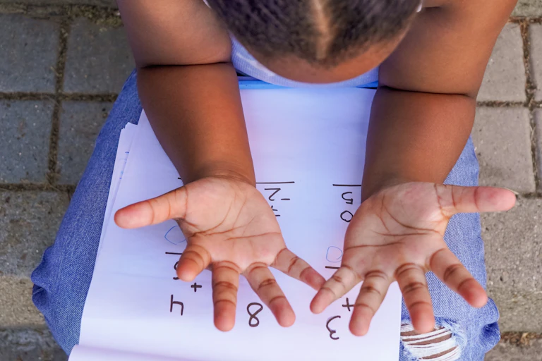 A child looks at her fingers.