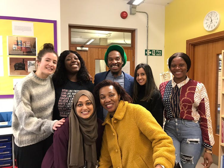 Benjamin Zephaniah poses for a photo in a room with a group of trainee teachers.