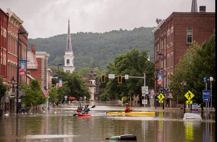 kayakers paddle down a flooded street