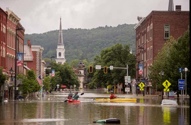 People kayak through flooded streets in downtown Montpelier, Vermont.