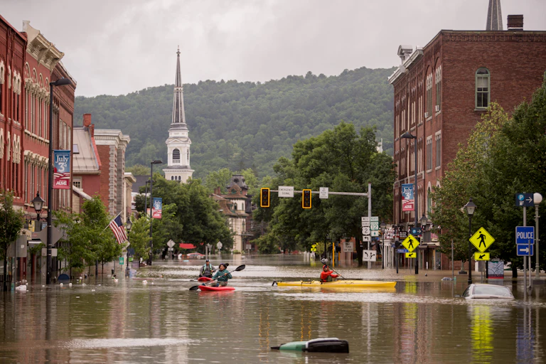 People kayak through flooded streets in downtown Montpelier, Vermont.