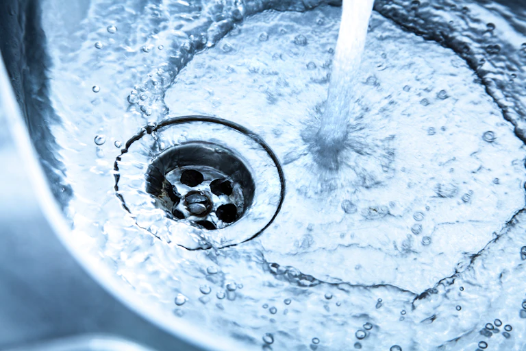 A stream of water running in a sink and down a drain