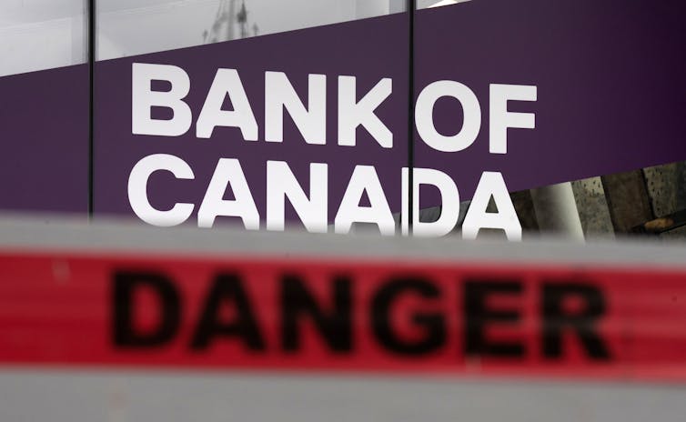 A red danger sign in front of a Bank of Canada sign.