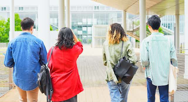 Four students walking across a campus with backs to the camera