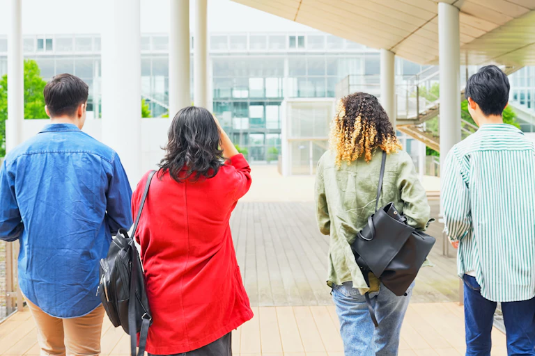 Four students walking across a campus with backs to the camera