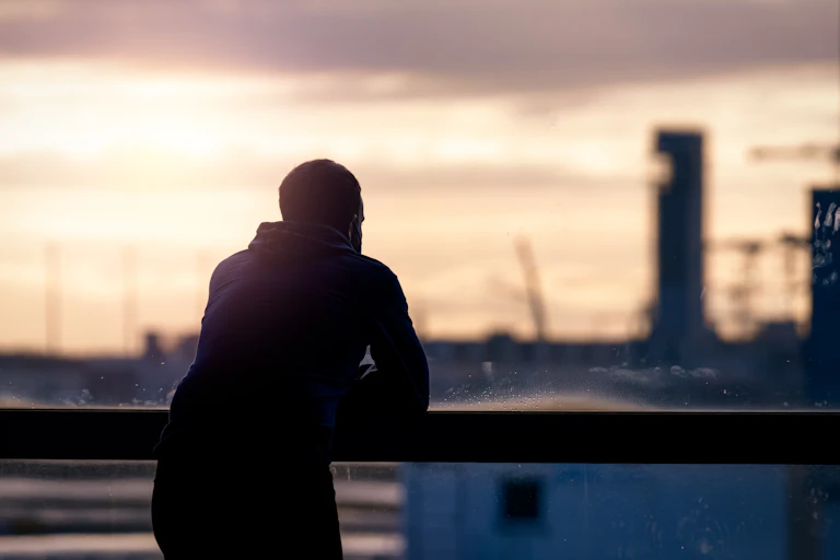Man stands looking out large window