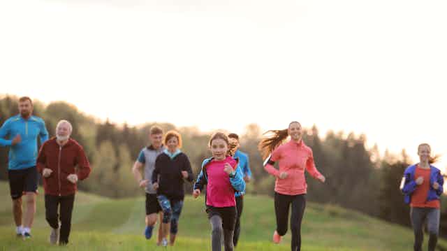 A group of adults and children of all ages running outdoors
