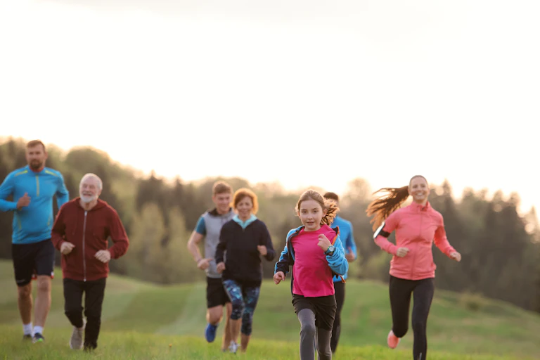 A group of adults and children of all ages running outdoors