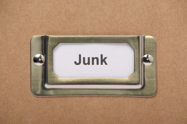 a metal bracket holding in place a small piece of paper with the word "junk" printed on it