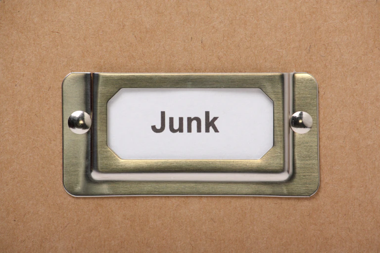 a metal bracket holding in place a small piece of paper with the word "junk" printed on it