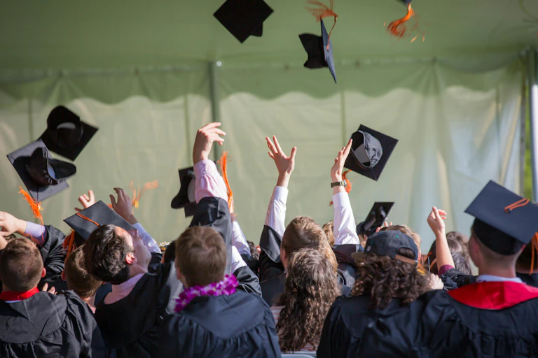 Graduates throw their mortar boards in the air.