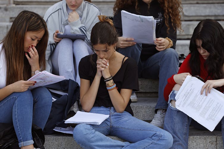 Students sit on steps, looking at notes.