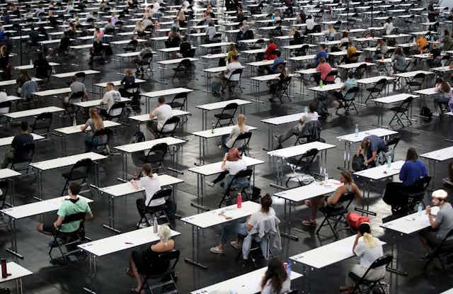 A vast hall is filled with students at separate tables for an exam.