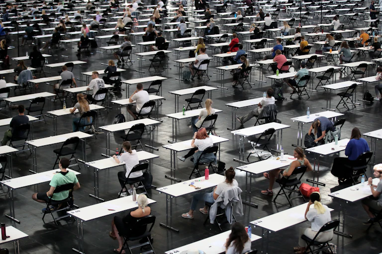 A vast hall is filled with students at separate tables for an exam.