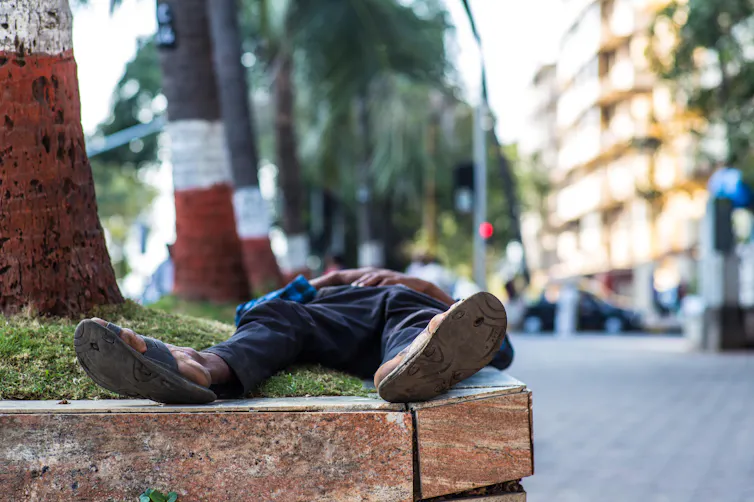 A man lying on a raised embankment in a city.