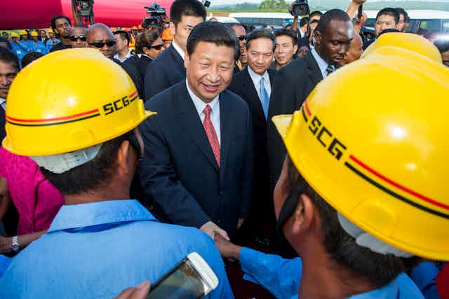 China's President Xi Jinping shakes hands with construction workers