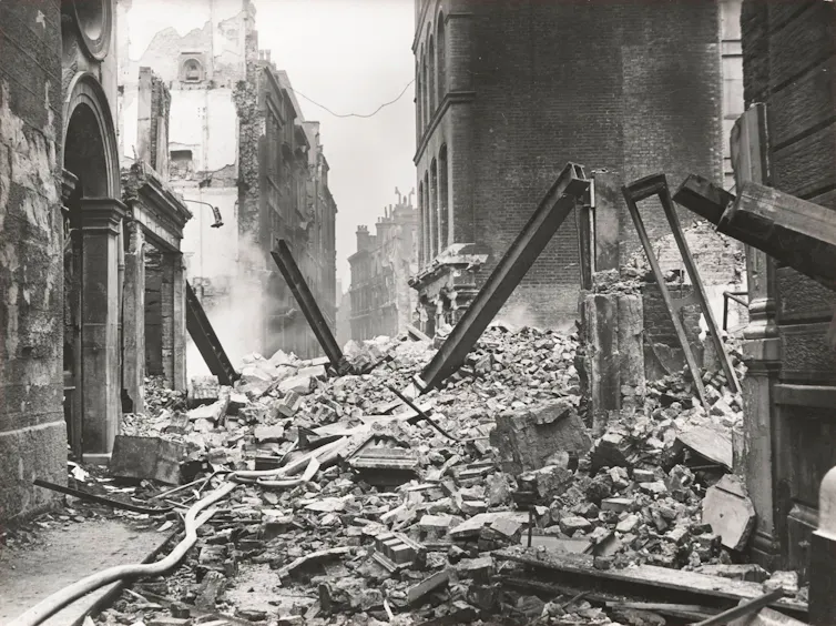 An archival photograph of a bombed out street in London.