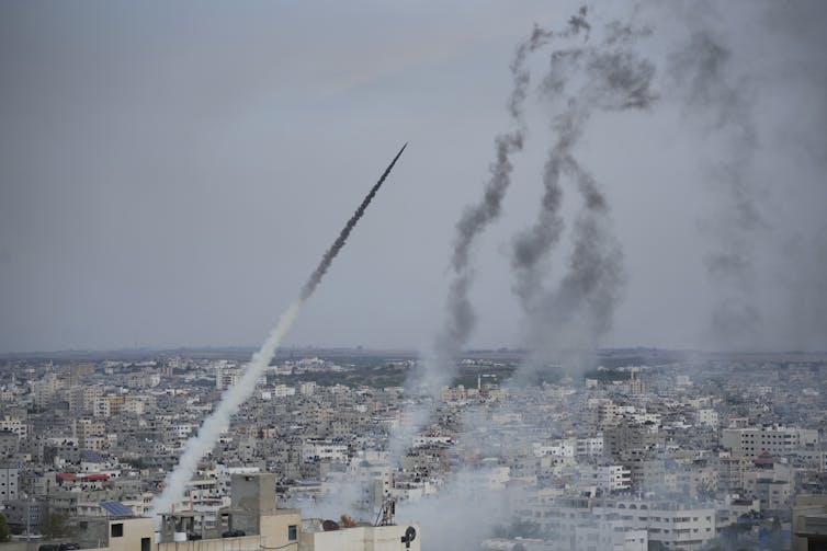 Smoke trails in the sky over an urban scene show where rockets have been fired.