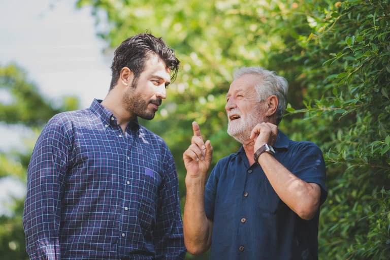 An older man talks to a younger man and imparts knowledge.
