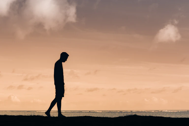 man walks outside with head down