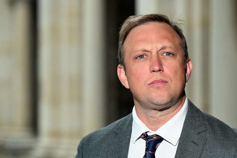 A man in a suit looks into the camera