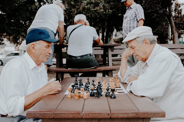 Old men play chess outside.