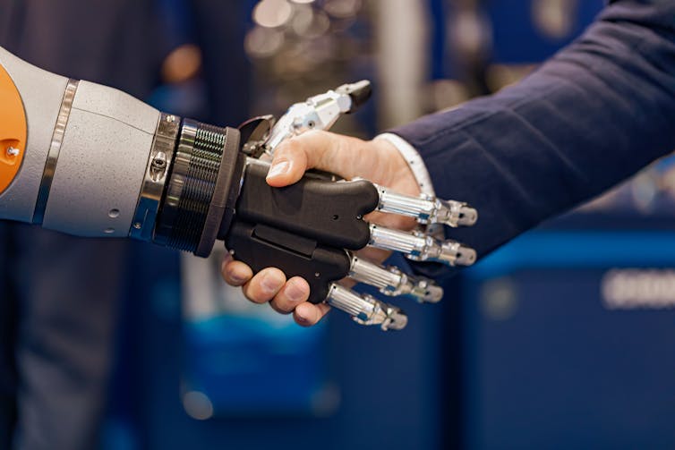 Robot hand shaking hands with a human male